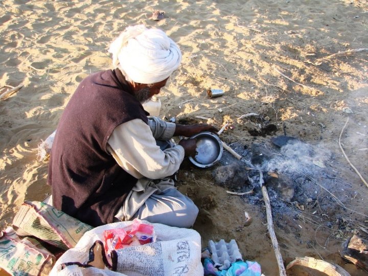 Jaisalmer camel safari - our guide cleans the utensils with sand